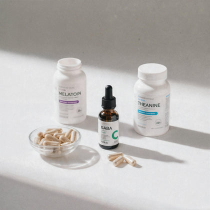 Colecție suplimente somn și relaxare: sticlă Melatonin cu etichetă mov, GABA lichid cu picurător, L-Theanine capsule și bol cu suplimente pe fundal alb minimalist